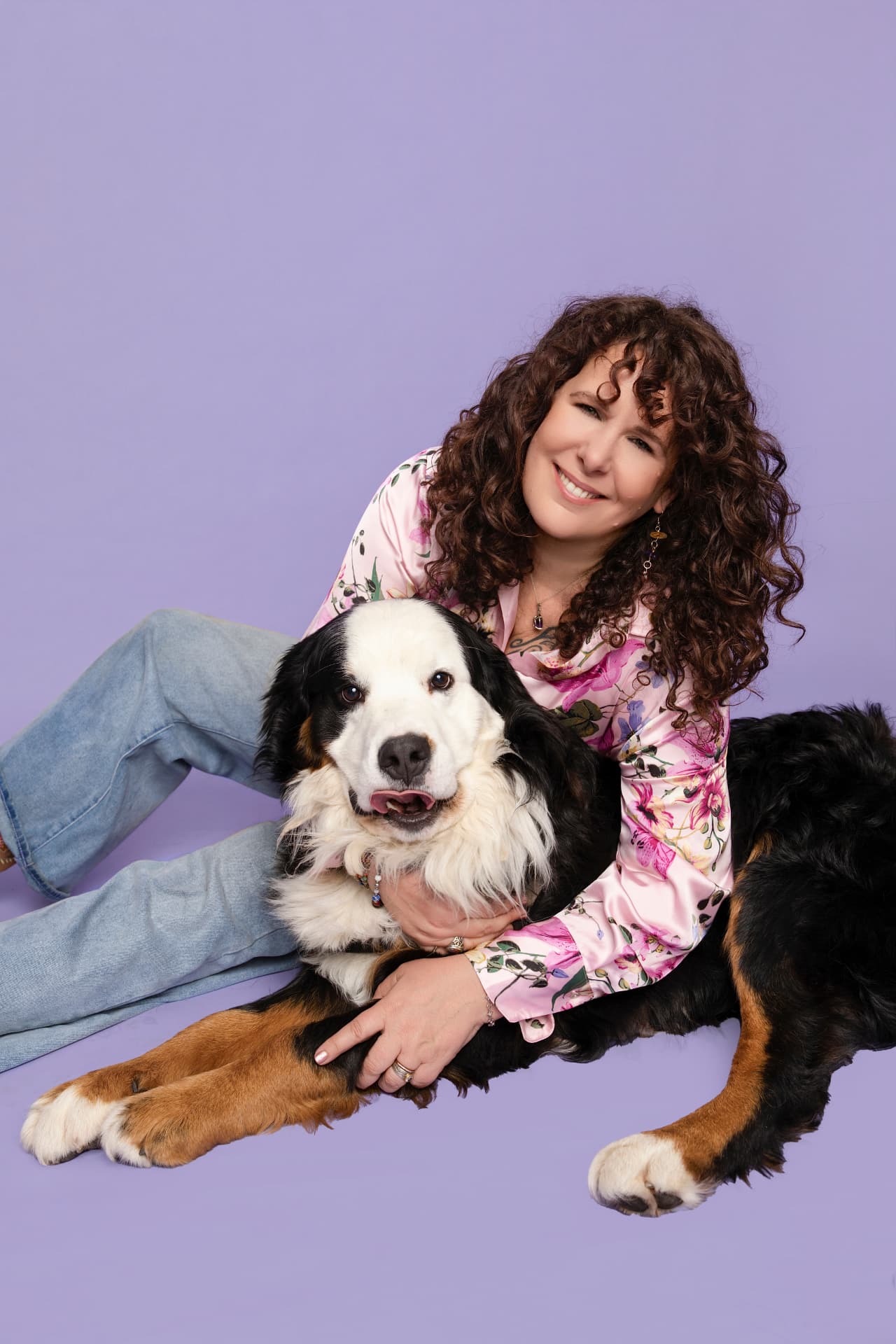 Luannah sitting on the floor, smiling, with her arms around her dog